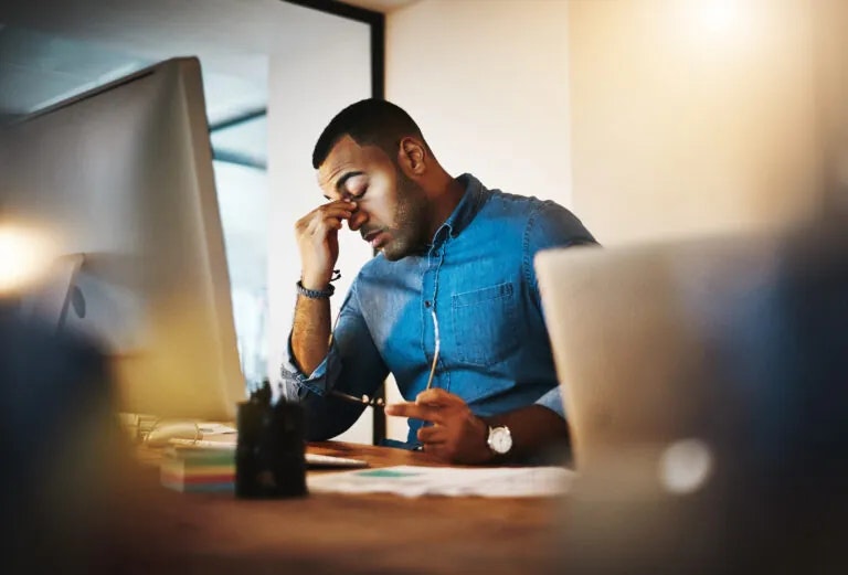 A tired but composed high-performing employee at a desk, illustrating hidden signs of burnout.